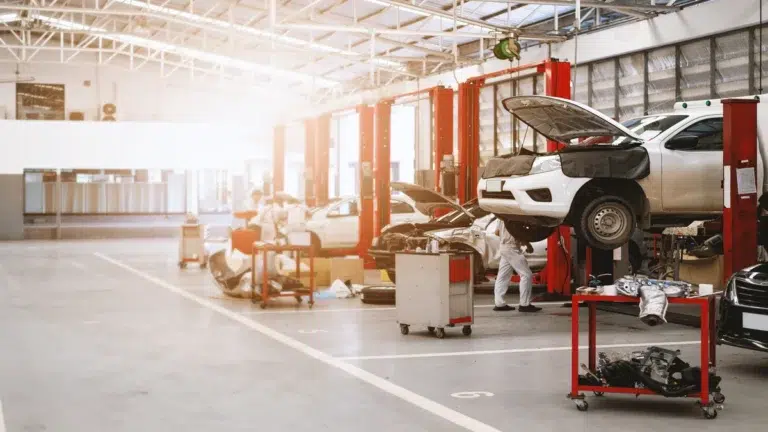 A car service workshop interior with vehicles raised on hydraulic lifts, surrounded by tools for inspecting and replacing bmw spare parts.