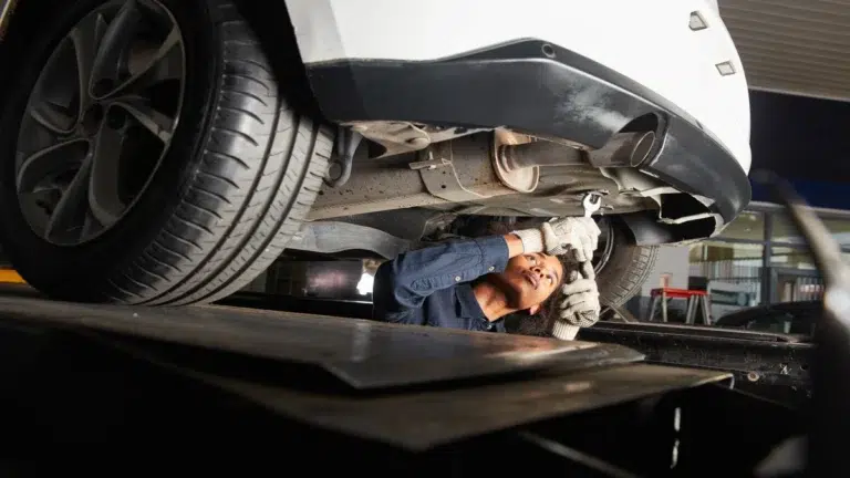 A mechanic performs expert checks under a car during a porsche car service.