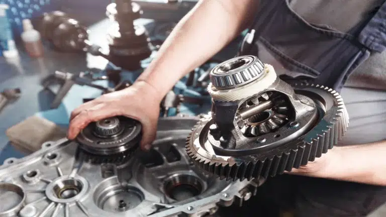 A mechanic inspecting a differential gear assembly while evaluating Range Rover spare parts.