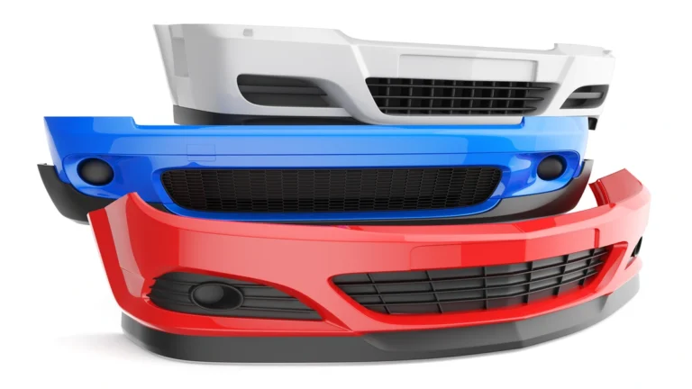 Stacked red, blue, and white car bumper covers for a Mercedes bumper replacement.