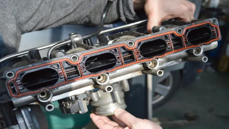 Mechanic holding an engine intake manifold provided by a trusted auto parts supplier.