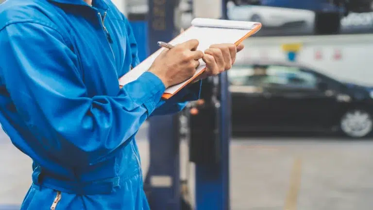 Technician filling out an inspection checklist for a Mercedes used parts supplier.